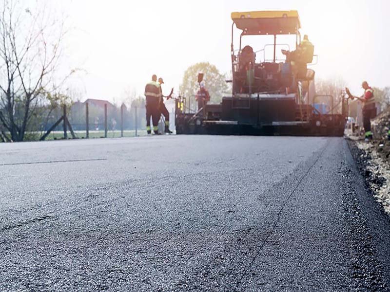 workers placing new coating asphalt road