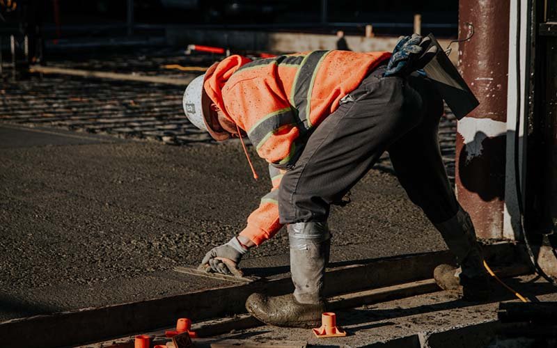 workers smoothing concrete in construction site