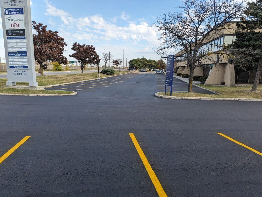 Newly marked parking lot with yellow lines in front of a business center with directory signage.