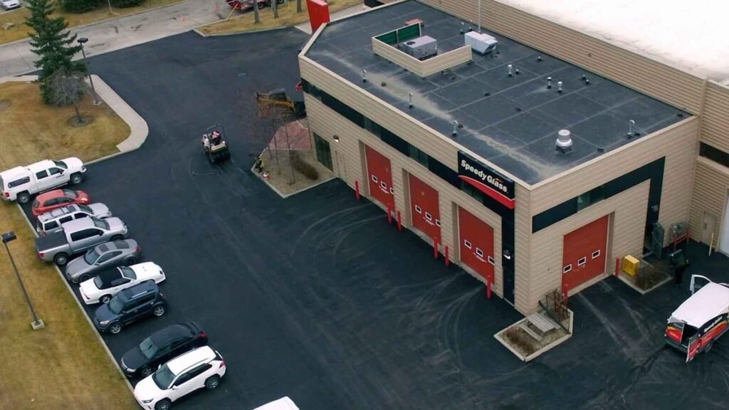 Aerial view of a Speedy Glass service center with parked cars and a service van on a freshly paved lot.