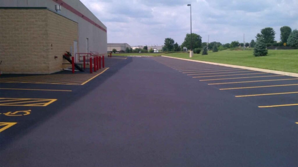 Empty parking lot with fresh yellow parking space lines next to a commercial building on a sunny day.